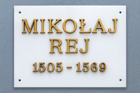 Tablica pamiątkowa z białego granitu z zamocowanymi mosiężnymi literami, upamiętniająca Mikołaja Reja z datami: 1505–1569